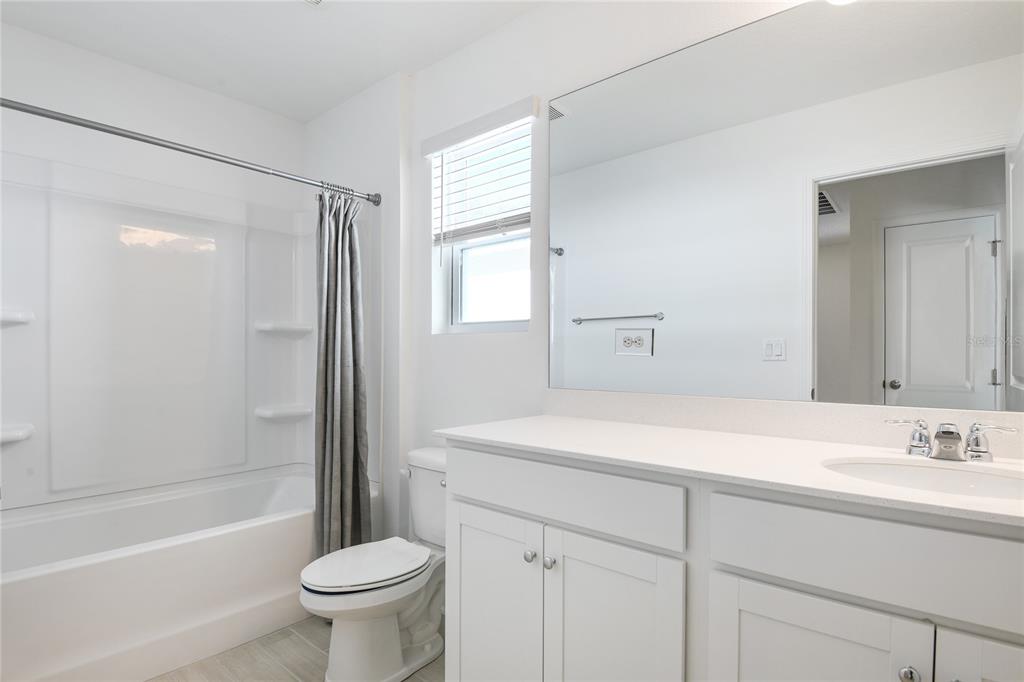 A bright bathroom features a white vanity, a large mirror, and a shower-tub combination — 5812 LAGOON CRUISE WAY, JACKSONVILLE, FL