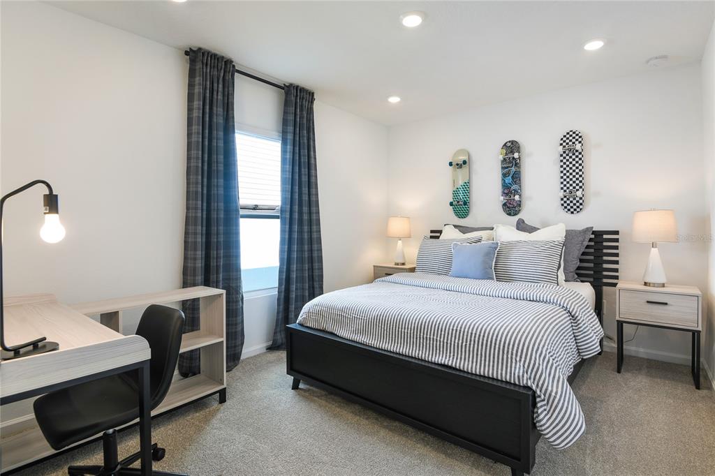 A bedroom features a bed with striped bedding, three skateboards on the wall, and a desk — 5812 LAGOON CRUISE WAY, JACKSONVILLE, FL