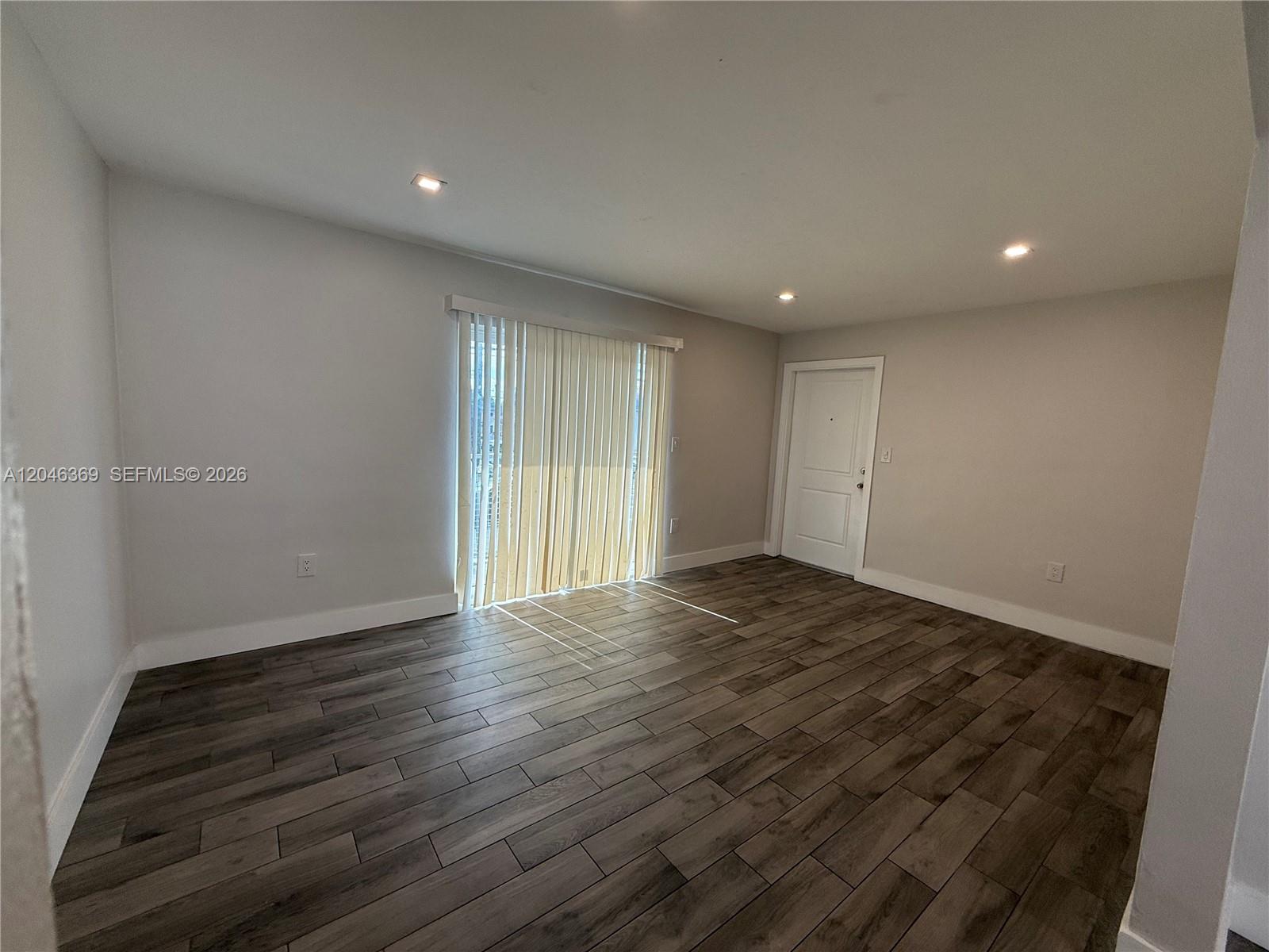 An empty room features light gray walls, recessed lighting, and dark wood-look tile flooring — 12th Street SE 12th St # 837, Hialeah FL 33010, HIALEAH, FL