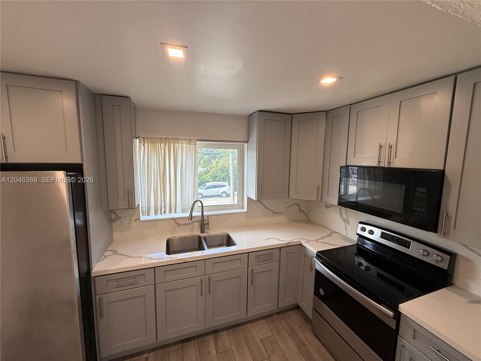 A kitchen features gray cabinets, white marble-look countertops, and stainless steel appliances — 12th Street SE 12th St # 837, Hialeah FL 33010, HIALEAH, FL