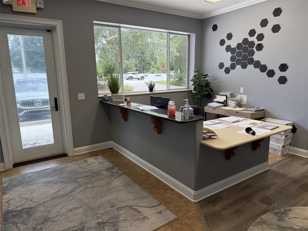 A reception area features a dark gray desk, a large window, and wall-mounted hexagonal decor — 1213 W MILLER STREET, FRUITLAND PARK, FL