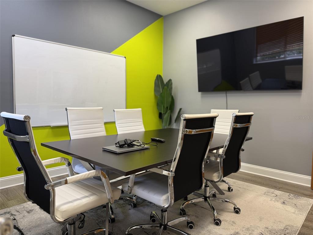 A conference room features a dark table, four chairs, a whiteboard, and a wall-mounted television — 1213 W MILLER STREET, FRUITLAND PARK, FL