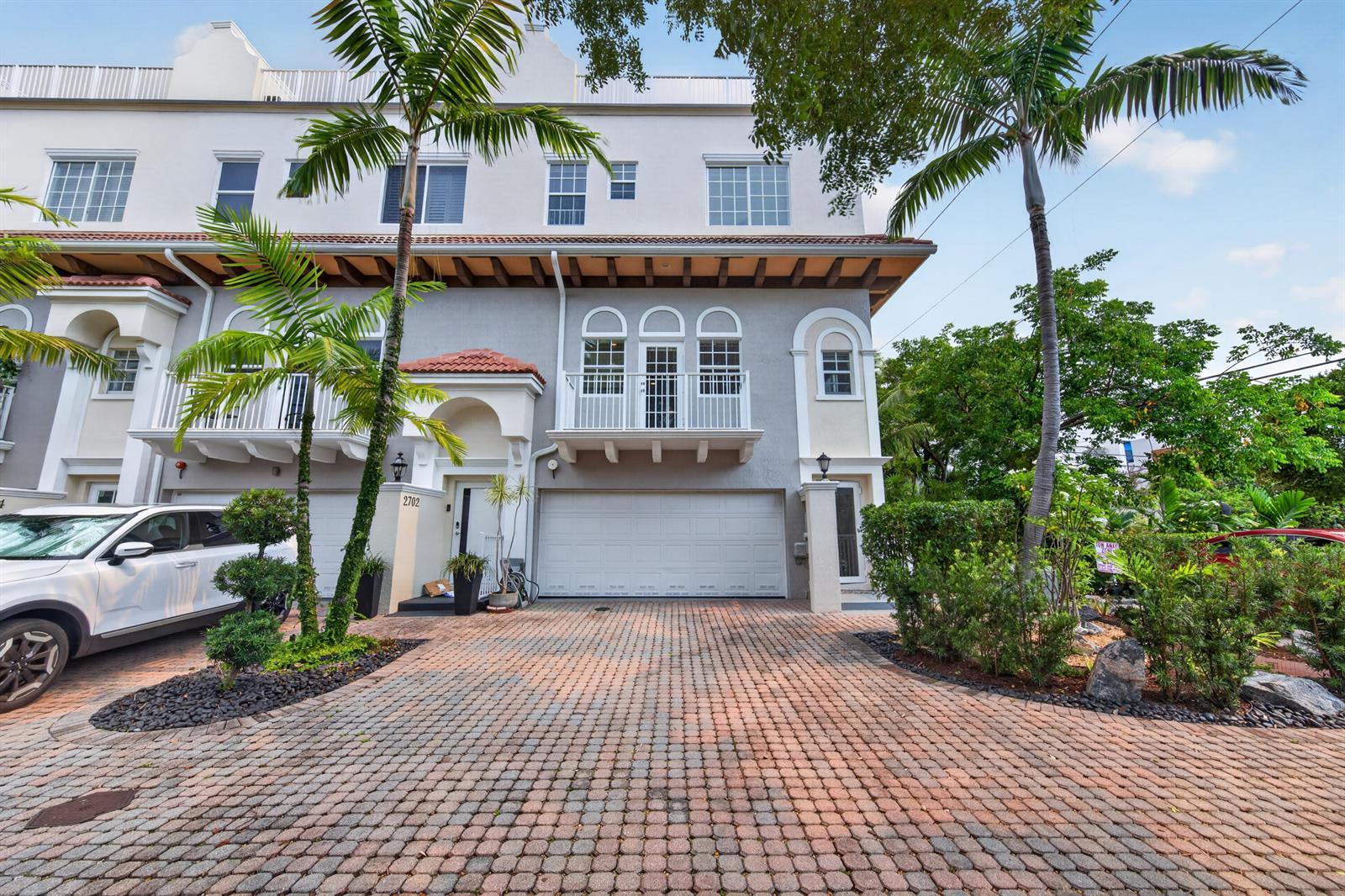 A three-story townhouse with a paved driveway, a two-car garage, and a second-floor balcony — 2700 NE 8th Avenue, Wilton Manors FL 33334, WILTON MANORS, FL