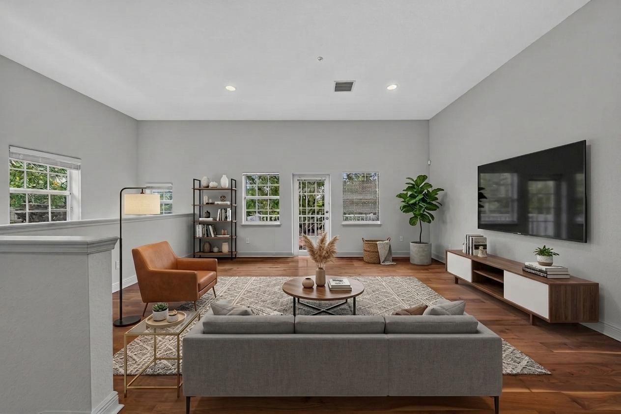 A living room features light gray walls, hardwood floors, a gray sofa, and a television — 2700 NE 8th Avenue, Wilton Manors FL 33334, WILTON MANORS, FL