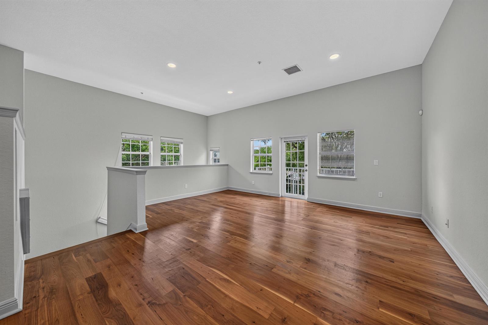 An empty loft space features hardwood floors, light gray walls, recessed lighting, and a balcony door — 2700 NE 8th Avenue, Wilton Manors FL 33334, WILTON MANORS, FL