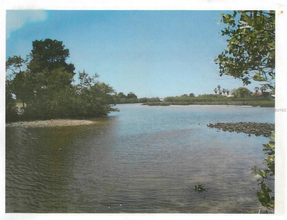 A view of a shallow waterway with mangroves and a rocky shoreline under a blue sky — 4218 RUDDER WAY, NEW PORT RICHEY, FL