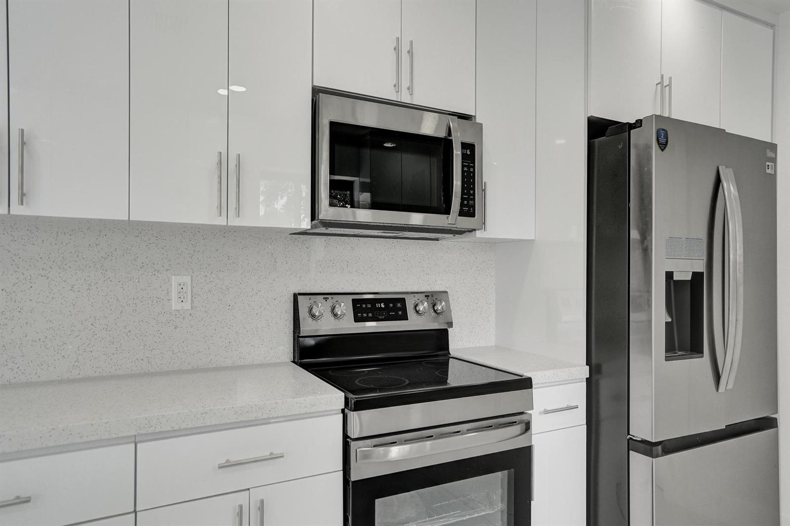 A kitchen features white cabinets, stainless steel appliances, and light-colored speckled countertops — 2301 Alcazar Drive, Miramar FL 33023, MIRAMAR, FL