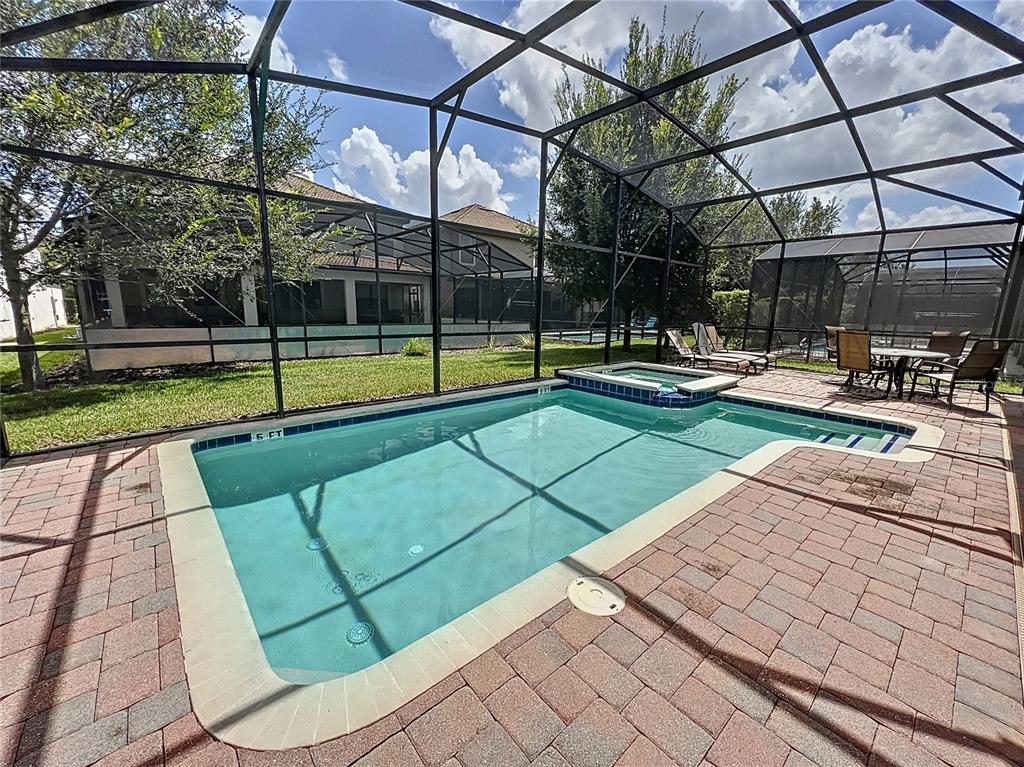 A swimming pool with an attached spa sits inside a screened enclosure on a patio — 1453 MYRTLEWOOD STREET, DAVENPORT, FL