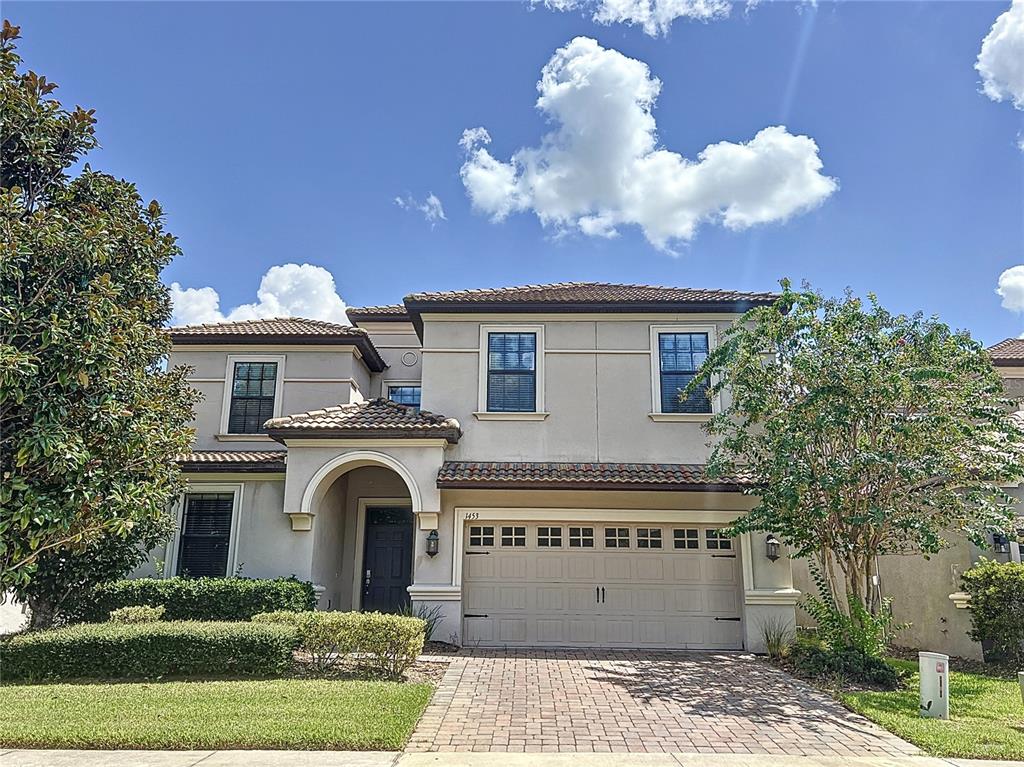 A two-story house with a beige stucco exterior, a tiled roof, and a paved driveway — 1453 MYRTLEWOOD STREET, DAVENPORT, FL