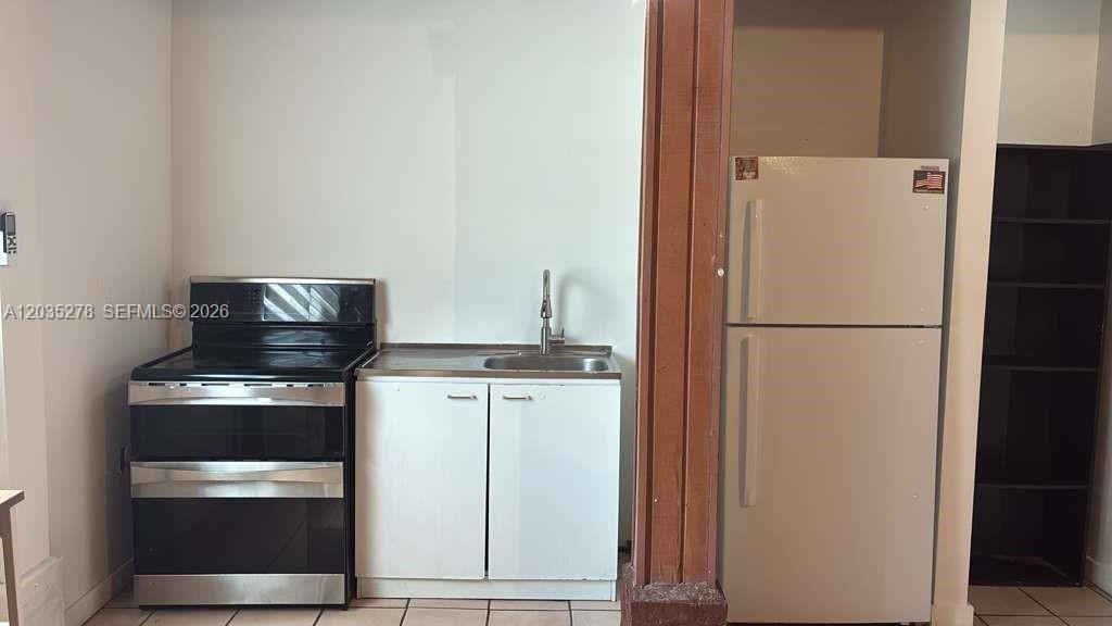 A small kitchen area features a stove, a sink cabinet, and a white refrigerator — 5950 NW 114th St- Efficiency 1,, Hialeah FL 33012, HIALEAH, FL