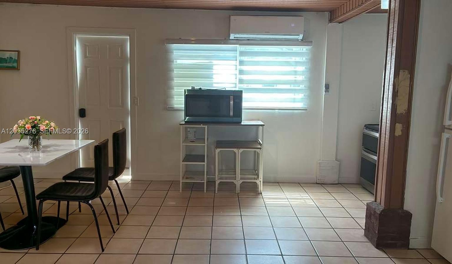 A dining area features a white table, black chairs, tile flooring, and a microwave stand — 5950 NW 114th St- Efficiency 1,, Hialeah FL 33012, HIALEAH, FL