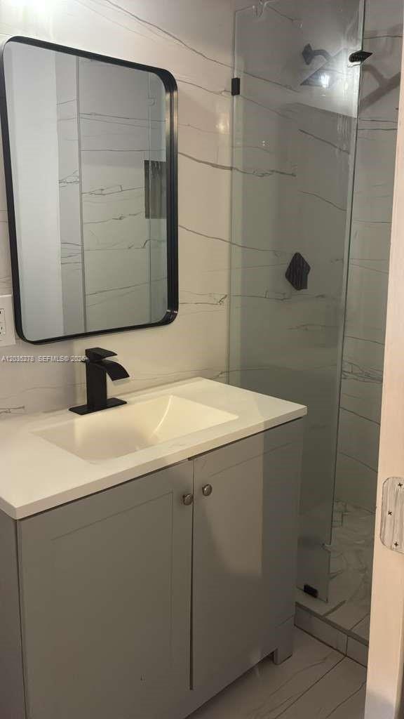 A modern bathroom features a gray vanity, white countertop, black faucet, and a glass-enclosed shower — 5950 NW 114th St- Efficiency 1,, Hialeah FL 33012, HIALEAH, FL