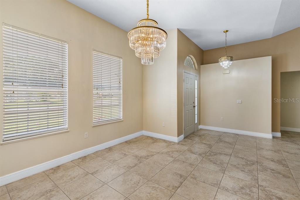 A dining room features tile flooring, two crystal chandeliers, and two windows with white blinds — 2326 JACKSON DRIVE, SEBRING, FL