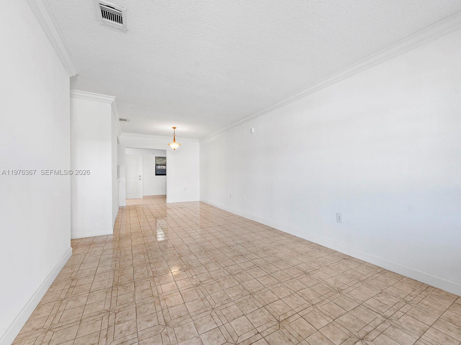 An empty room features white walls, crown molding, and light-colored square floor tiles — 7121 SW 102nd Ct, Miami FL 33173, MIAMI, FL