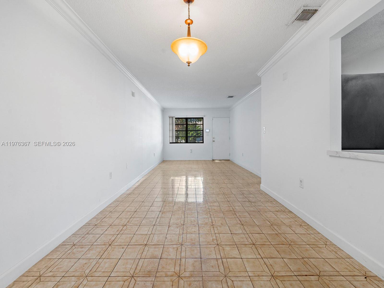 An empty room features white walls, a tiled floor, and a hanging light fixture — 7121 SW 102nd Ct, Miami FL 33173, MIAMI, FL