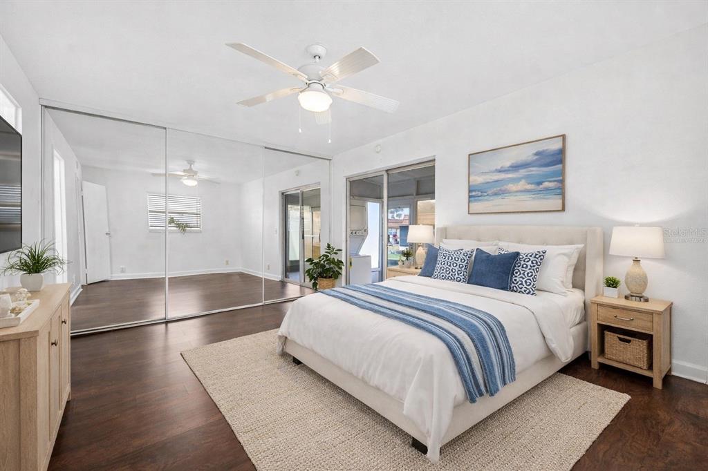 A bedroom with a bed, mirrored closet doors, a ceiling fan, and wood-look flooring — 1801 BEDFORD LANE UNIT 27, SUN CITY CENTER, FL