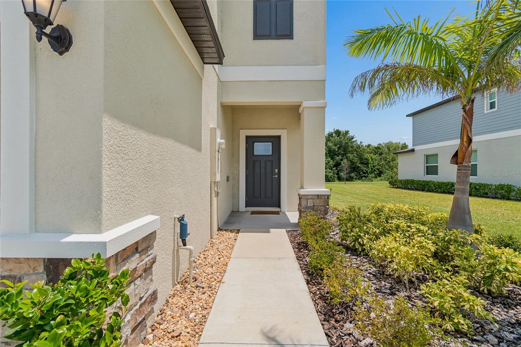 A concrete walkway leads to the dark front door of a two-story stucco home — 222 TULIP BANDED WAY, RUSKIN, FL