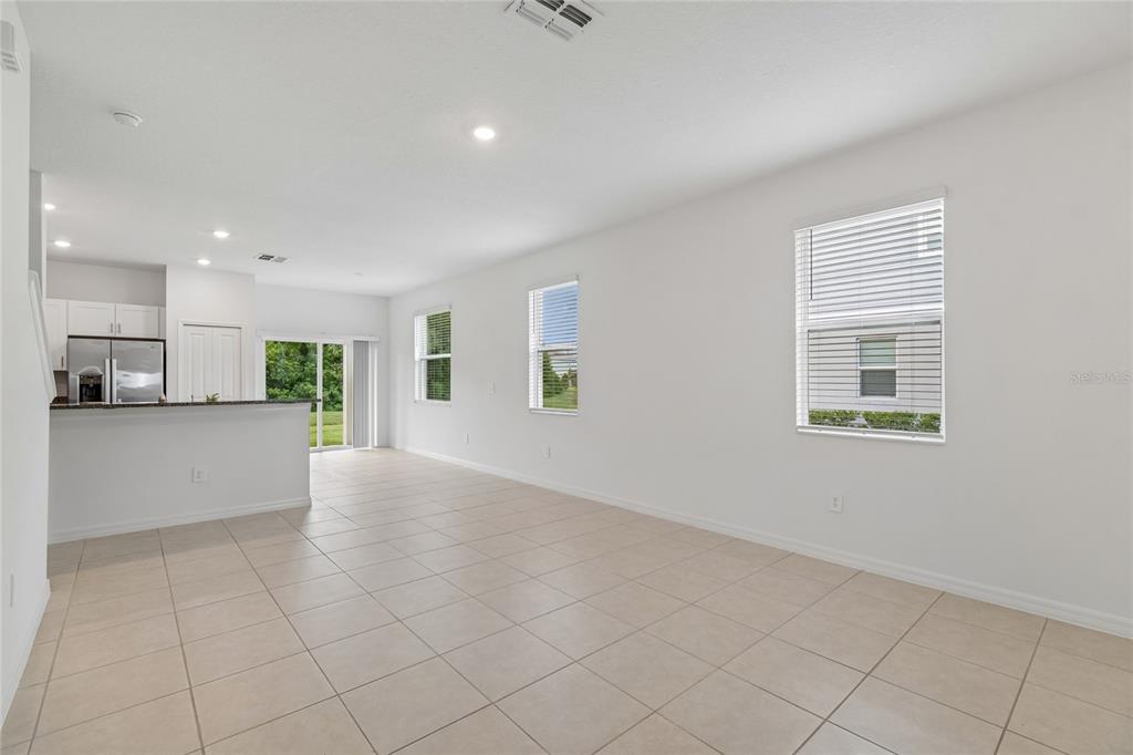 An open-concept living area with white walls, tile flooring, and a kitchen with granite countertops — 222 TULIP BANDED WAY, RUSKIN, FL