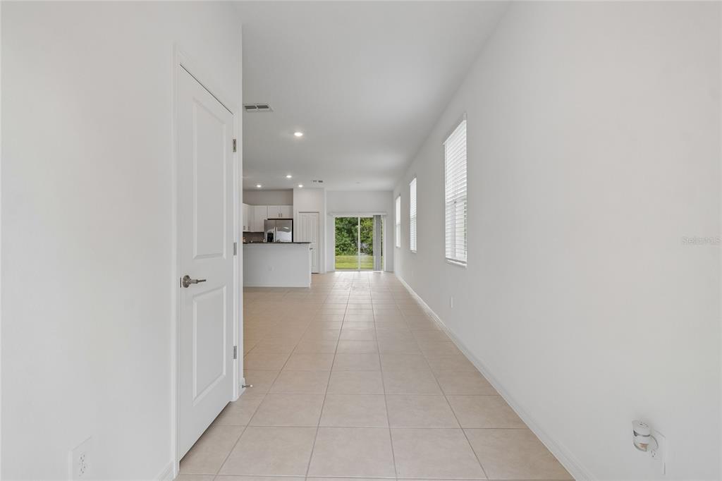 A tiled hallway leads to an open-concept kitchen and living area with sliding glass doors — 222 TULIP BANDED WAY, RUSKIN, FL