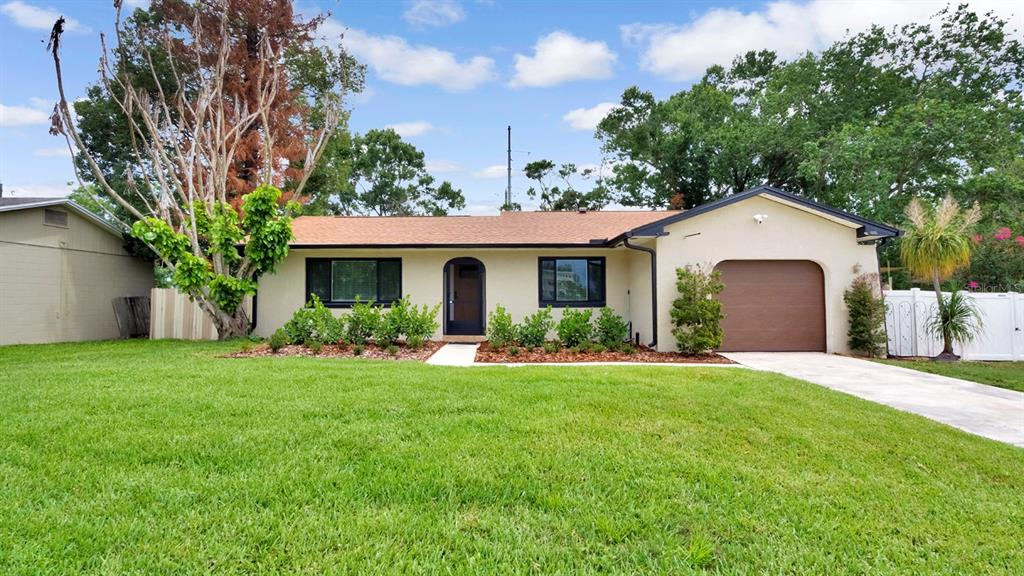 A single-story house with a tan exterior, brown garage door, and a front lawn — 7577 DOCKSIDE STREET, WINTER PARK, FL