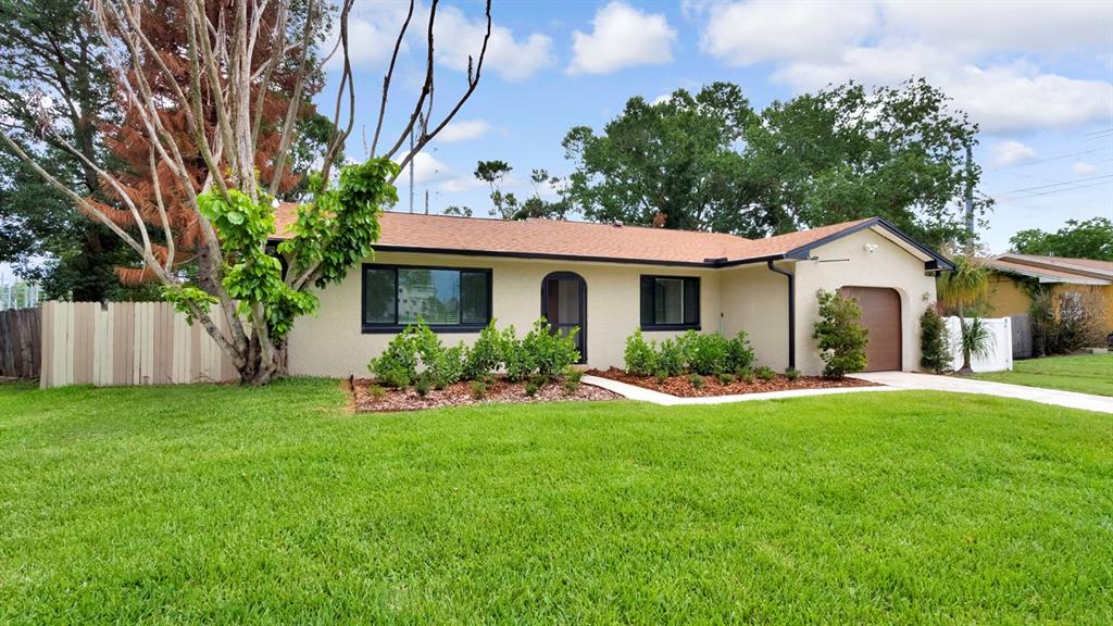 A single-story house with a tan stucco exterior, dark trim, and a front-facing garage — 7577 DOCKSIDE STREET, WINTER PARK, FL