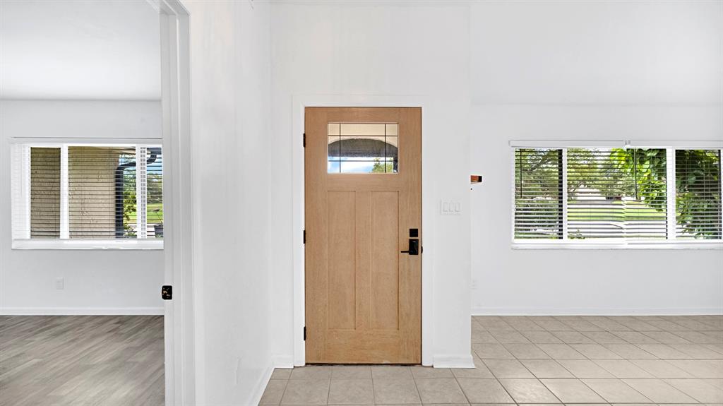 An interior view shows a wooden front door, tiled flooring, and windows with blinds — 7577 DOCKSIDE STREET, WINTER PARK, FL