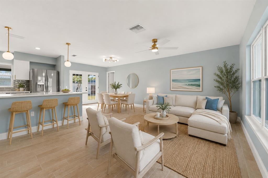 An open-concept living and dining area features light blue walls, neutral furniture, and wood-look tile — 3356 PLANTATION PLACE, SARASOTA, FL