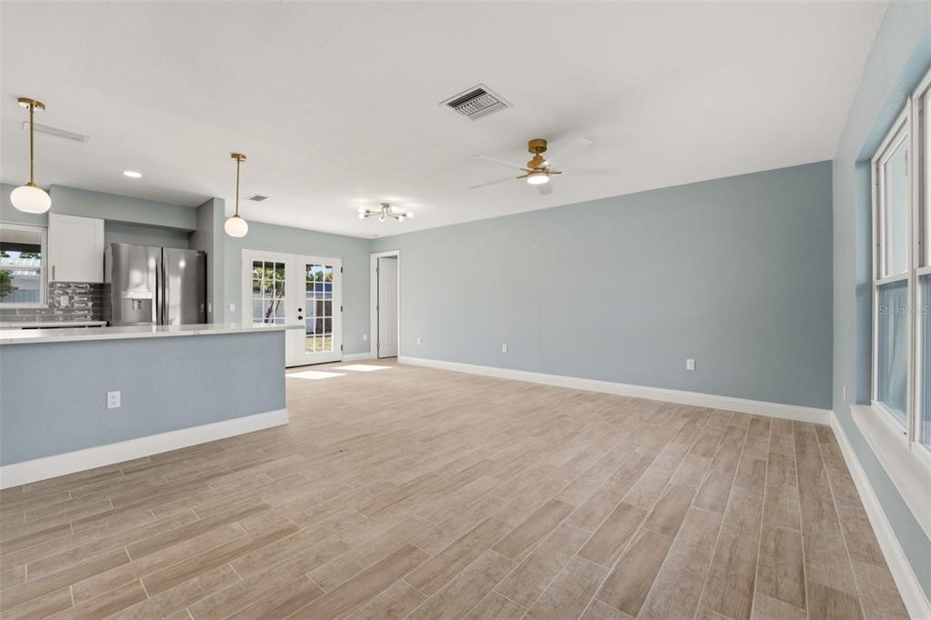 An open-concept living area features light blue walls, wood-look tile flooring, and a kitchen island — 3356 PLANTATION PLACE, SARASOTA, FL