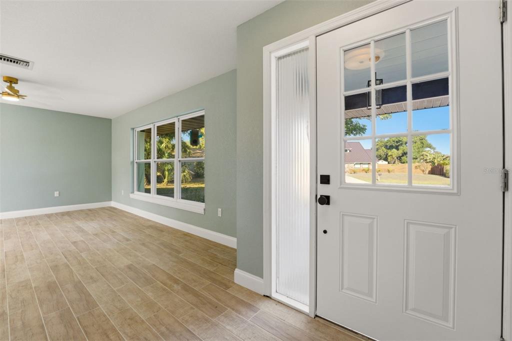 An interior view of an entryway with light wood-look tile floors and a white door — 3356 PLANTATION PLACE, SARASOTA, FL