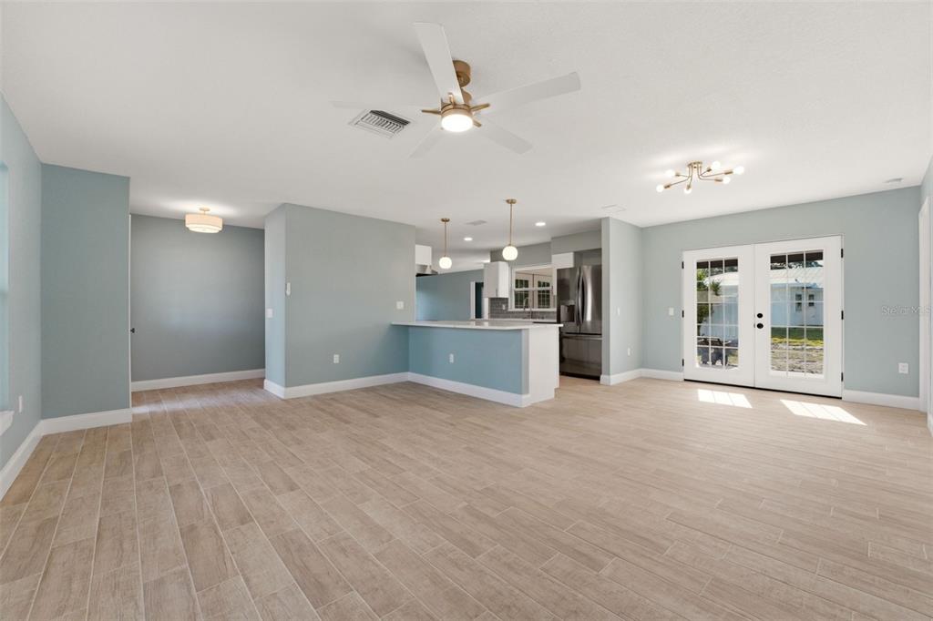 An open-concept living area features light blue walls, wood-look tile flooring, and a kitchen island — 3356 PLANTATION PLACE, SARASOTA, FL