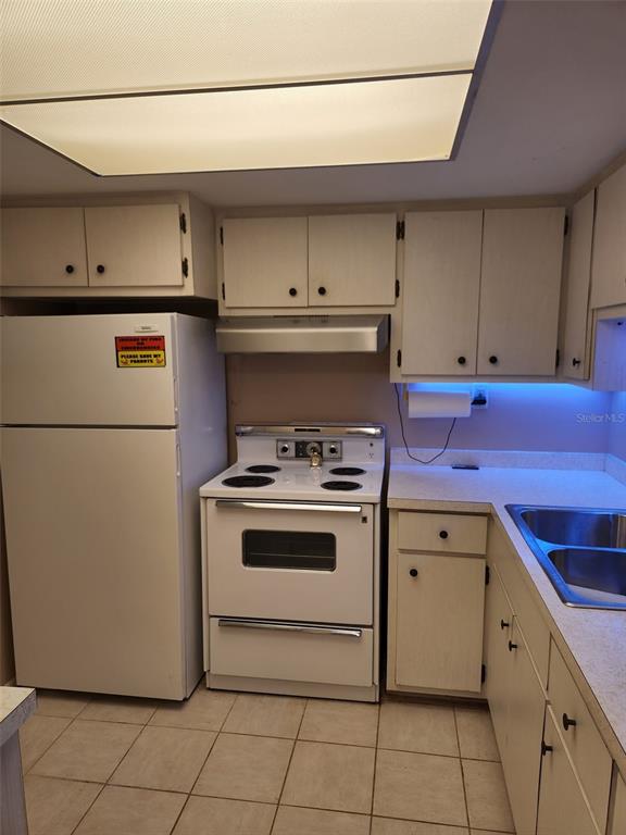 A kitchen features white cabinets, a white refrigerator, a white stove, and a double sink — 3100 HARBOR BOULEVARD UNIT 102, PORT CHARLOTTE, FL
