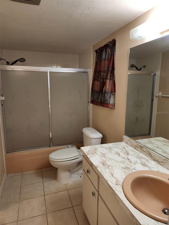 A bathroom features a peach-colored tub and sink, a toilet, and a sliding shower door — 3100 HARBOR BOULEVARD UNIT 102, PORT CHARLOTTE, FL
