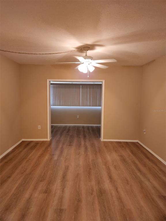 An interior view shows a living area with wood-look flooring leading to an adjacent room — 3100 HARBOR BOULEVARD UNIT 102, PORT CHARLOTTE, FL