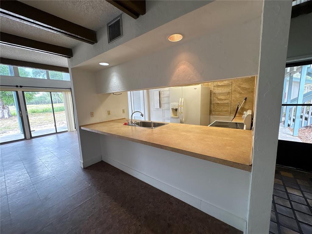 A kitchen with a pass-through counter, laminate countertops, and a view of the living area — 2010 CORNER LAKE DRIVE UNIT 2010, HAINES CITY, FL