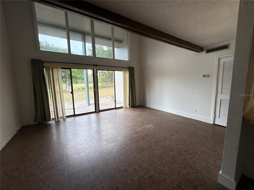 A living room features high ceilings, a large window wall, sliding glass doors, and tile flooring — 2010 CORNER LAKE DRIVE UNIT 2010, HAINES CITY, FL