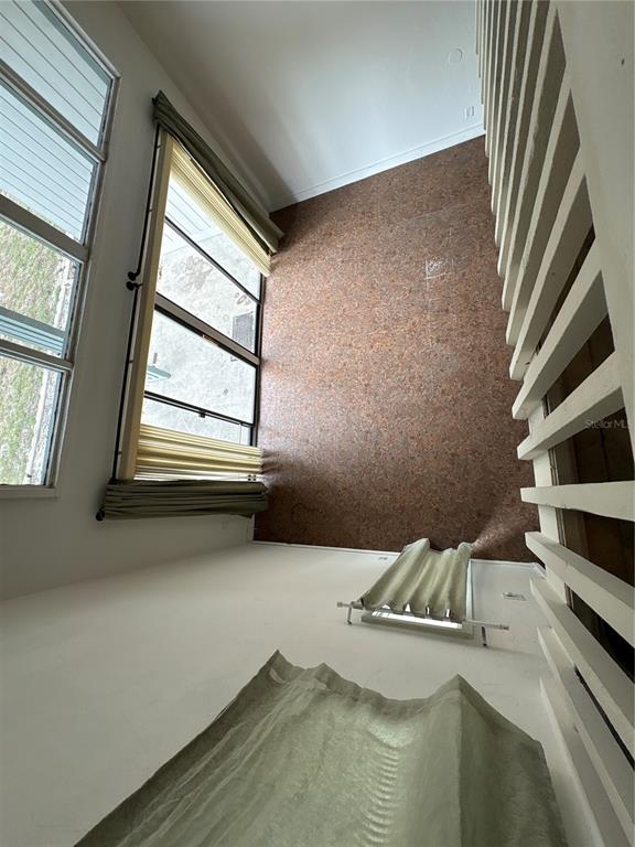 A high-ceilinged room features a textured brown accent wall, large windows, and slatted wall panels — 2010 CORNER LAKE DRIVE UNIT 2010, HAINES CITY, FL