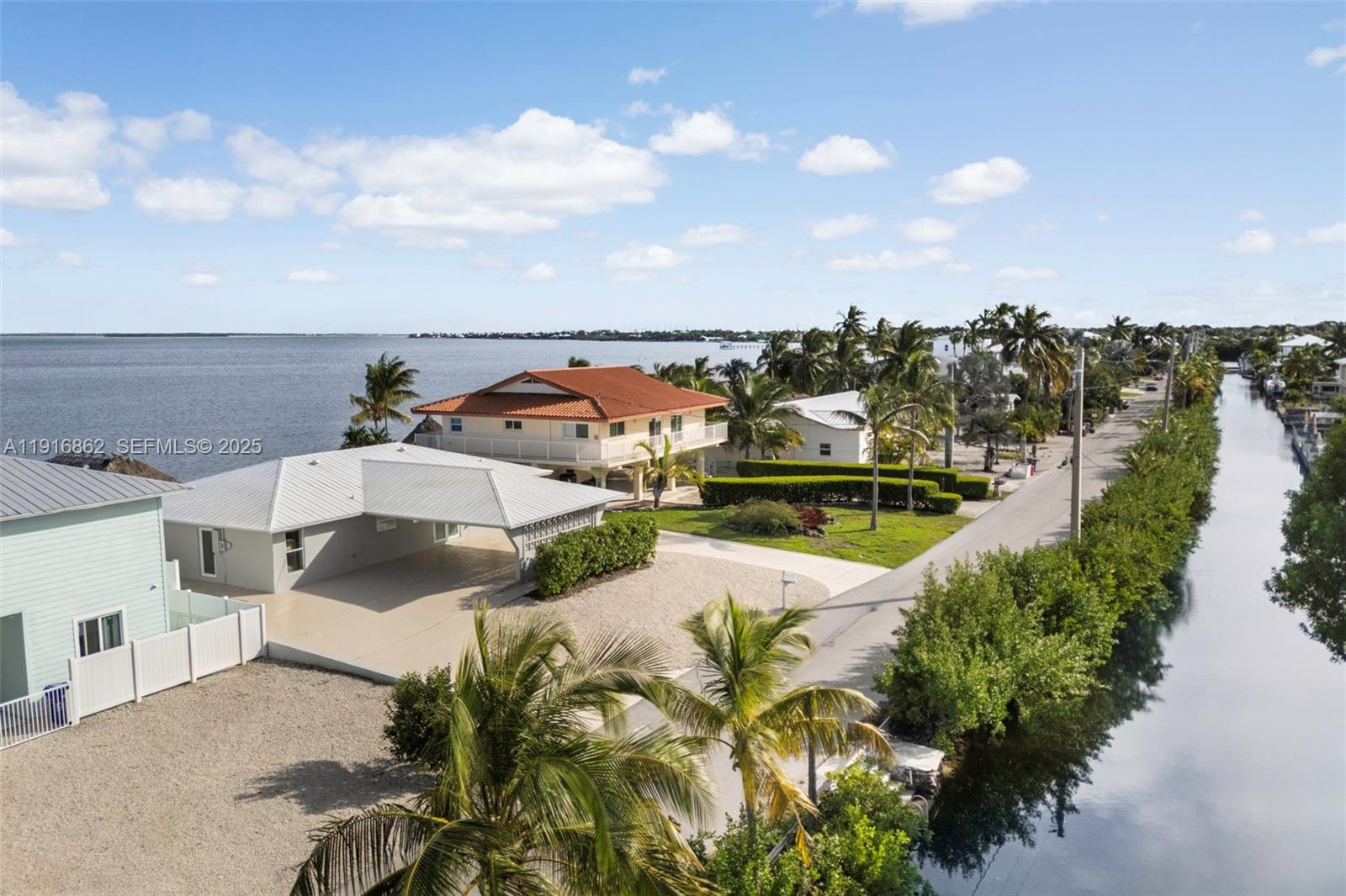 An aerial view shows a coastal neighborhood with houses, palm trees, and a canal — 1733 Sunrise Dr, Big Pine FL 33043, BIG PINE, FL