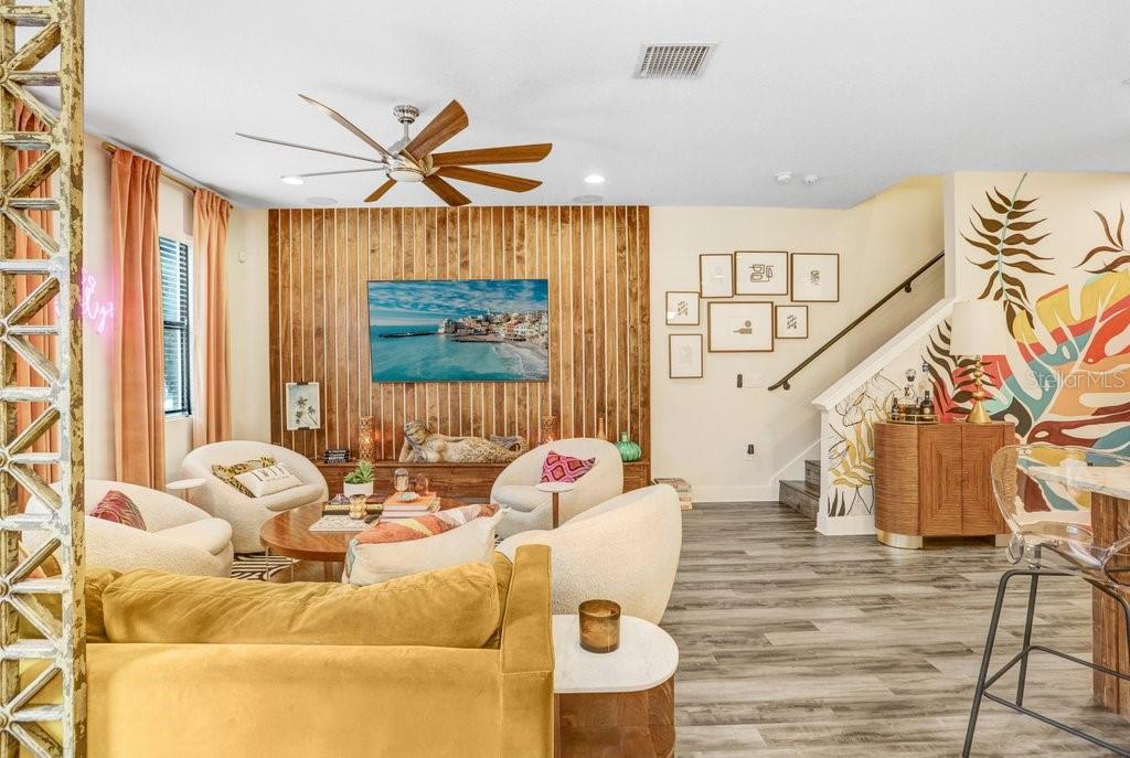 A living room features a wood-slat accent wall, a television, and a tropical mural — 1210 25TH STREET N, ST PETERSBURG, FL