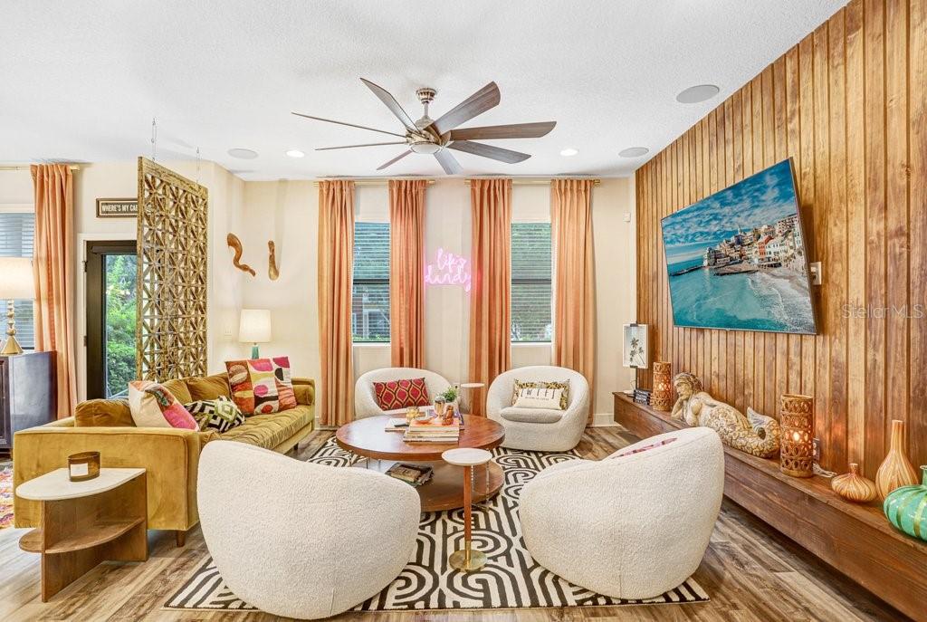 A living room features a wood-paneled accent wall, a large television, and a patterned rug — 1210 25TH STREET N, ST PETERSBURG, FL