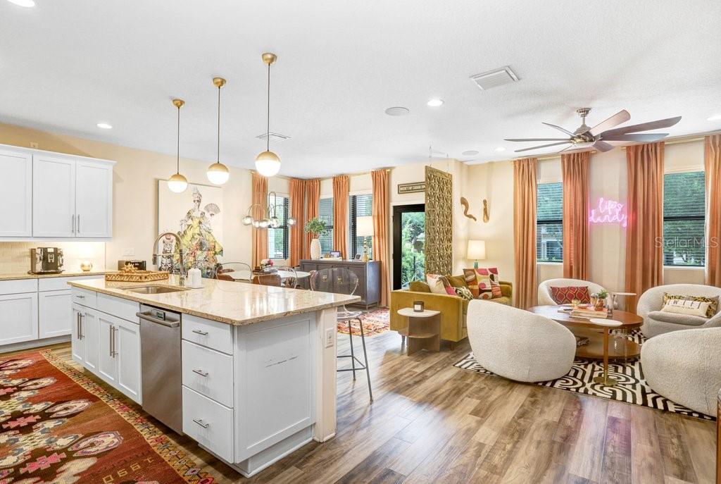 An open-concept kitchen with a granite island overlooks a living area with wood-look flooring — 1210 25TH STREET N, ST PETERSBURG, FL