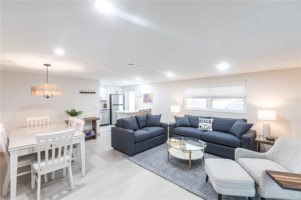 An open-concept living and dining area features white furniture, blue sofas, and light flooring — 6154 MIDNIGHT PASS ROAD UNIT B18, SARASOTA, FL
