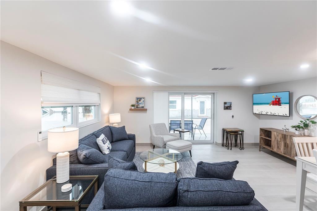 A living room features a blue sectional sofa, a glass coffee table, and a wall-mounted television — 6154 MIDNIGHT PASS ROAD UNIT B18, SARASOTA, FL