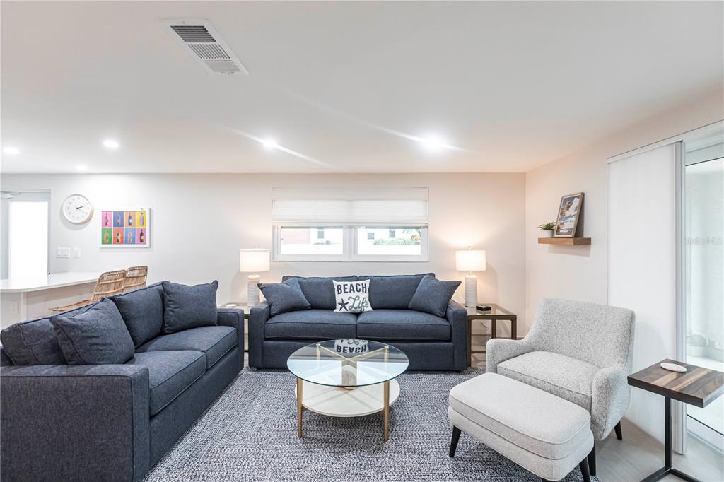 A living room features two dark blue sofas, a light gray armchair, and a glass-topped table — 6154 MIDNIGHT PASS ROAD UNIT B18, SARASOTA, FL