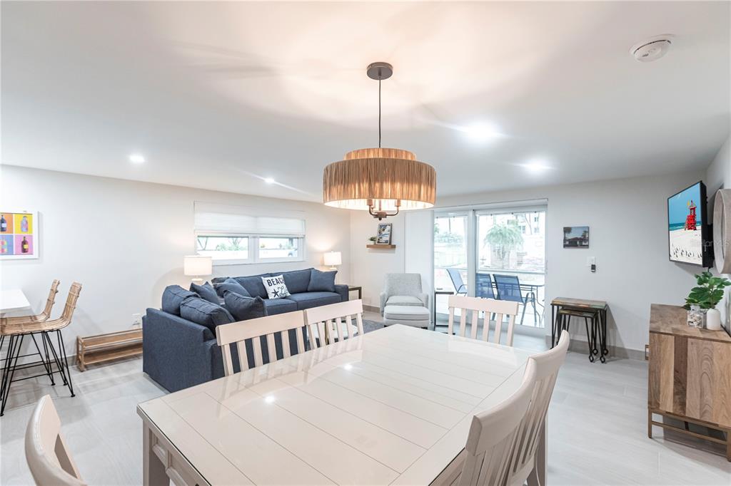 A dining area with a white table and chairs sits in front of a living room — 6154 MIDNIGHT PASS ROAD UNIT B18, SARASOTA, FL