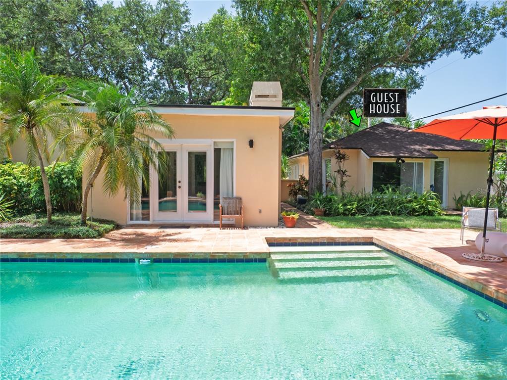 A swimming pool sits in front of a tan house and a separate guest house — 1330 INDIAN ROCKS ROAD, BELLEAIR, FL