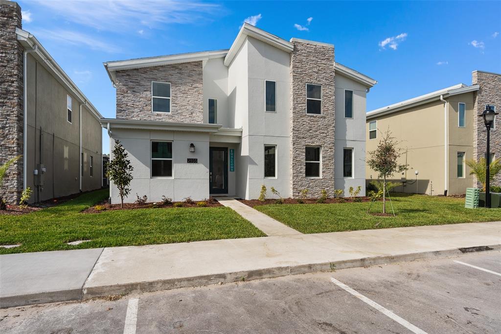 A two-story house with a white stucco facade, stone accents, and a concrete walkway — 2855 BOOKMARK DRIVE, KISSIMMEE, FL