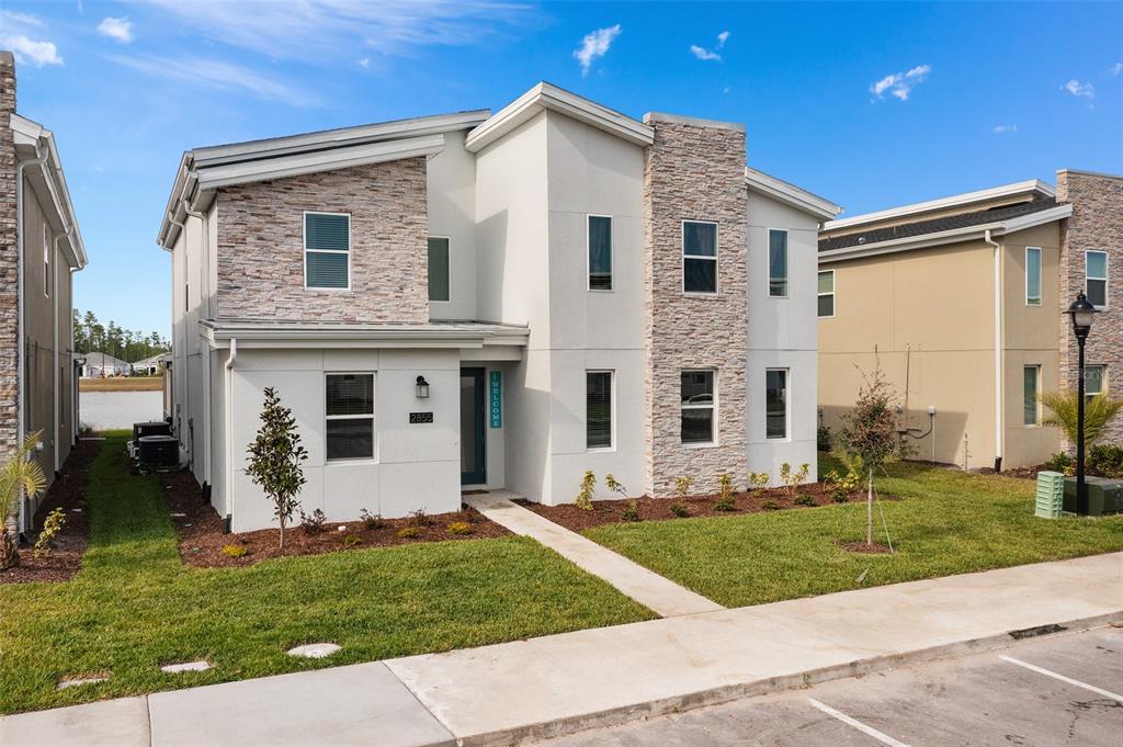 A two-story house features a stone veneer facade, white stucco walls, and a front walkway — 2855 BOOKMARK DRIVE, KISSIMMEE, FL