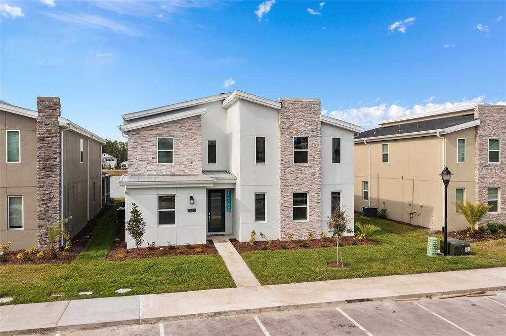 A two-story house with a stone and white facade sits next to a lake — 2855 BOOKMARK DRIVE, KISSIMMEE, FL