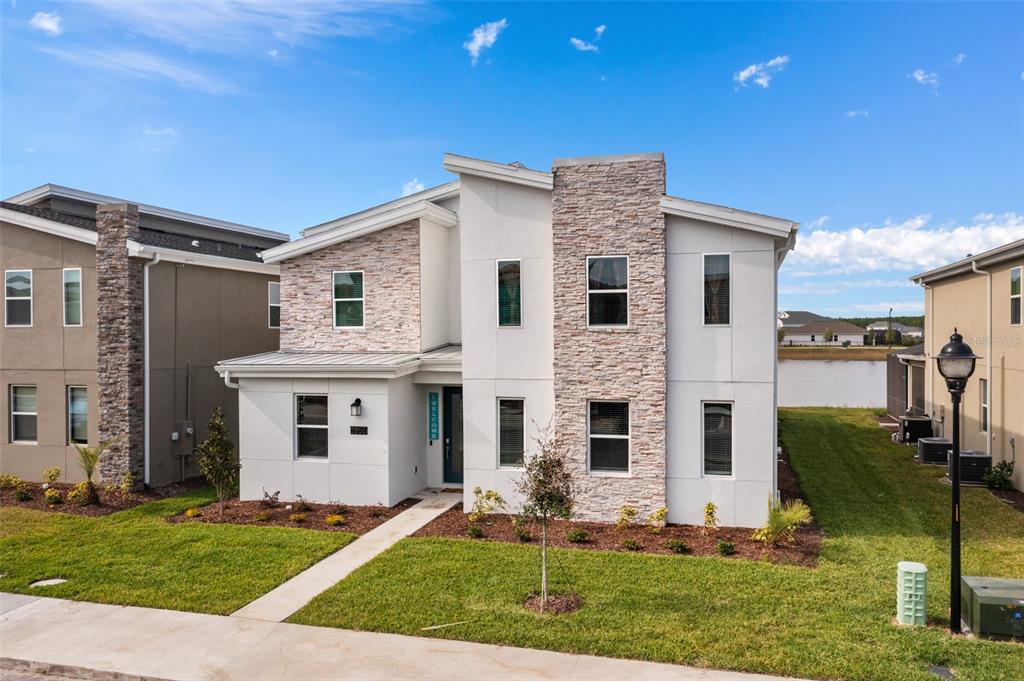 A two-story modern house with a stone facade, white stucco, and a front walkway — 2855 BOOKMARK DRIVE, KISSIMMEE, FL