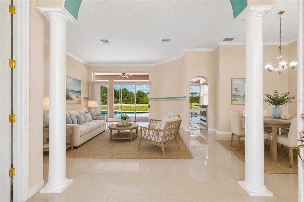 An entryway leads into a living room and dining area with tile floors and pool views — 18107 EMERALD BAY STREET, TAMPA, FL